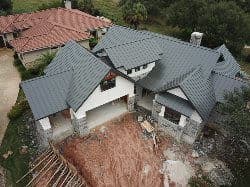 Aerial view of a partially constructed house with a modern design and metal roof.