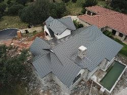 Aerial view of a modern home with a gray metal roof and surrounding landscaping.