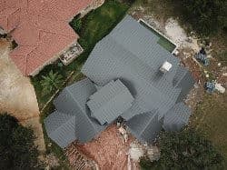 Aerial view of a modern house with a gray roof and surrounding construction site.