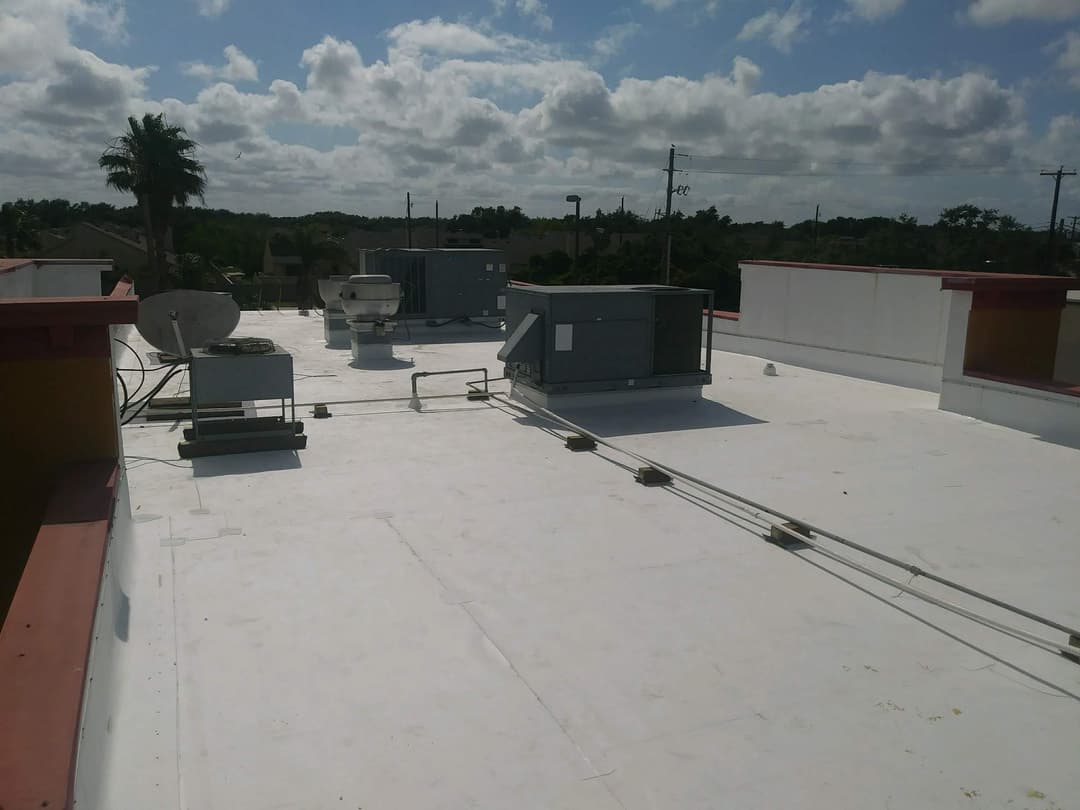 Flat roof with HVAC units, satellite dishes, and clear blue sky in the background.