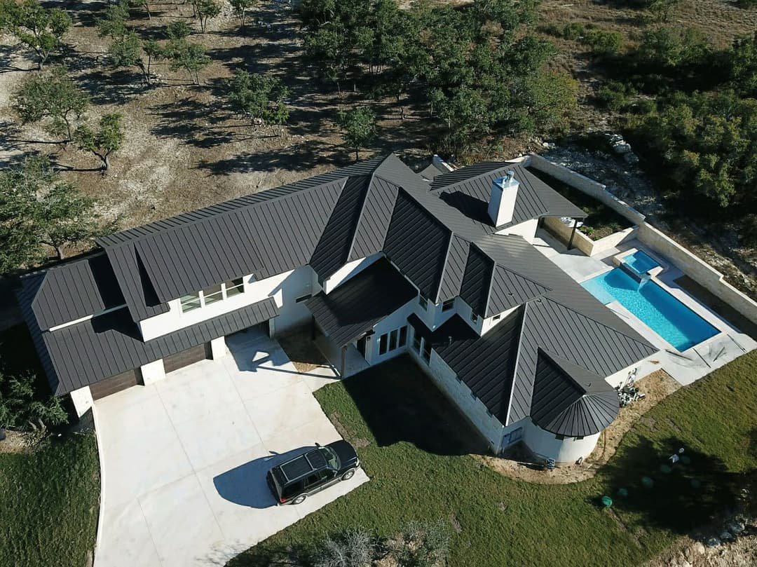 Aerial view of a modern home with a pool and surrounding landscape.