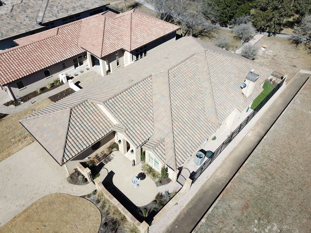 Aerial view of a modern home with tile roof and landscaped yard.