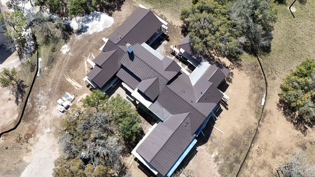 Aerial view of a residential construction site featuring a newly roofed home.
